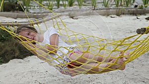 Young girl relaxing in a hammock on the sea beach