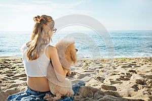 Young girl is resting with a dog on the sea.