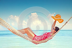 Young girl resting in a hammock under tall palm trees, tropical beach