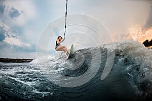 Young girl rides on a wakeboard in the river near forest