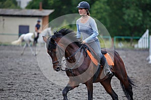 Young girl riding bay horse on equestrian sport training