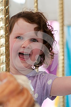 Young girl riding on fairground horse on carousel amusement ride at fairgrounds park outdoor