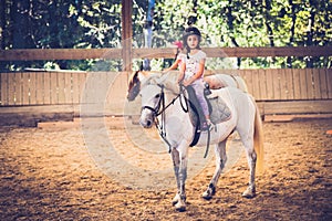 A young girl riding a horse in arena.