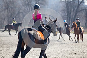 Young girl riding horse on equestrian training