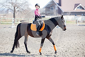 Young girl riding horse on equestrian training