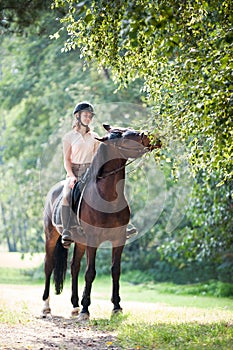 Young girl riding horseback at early morning in sunbeam
