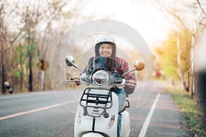 Young girl riding a motor scooter on road.