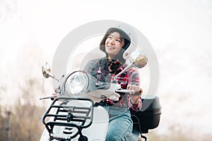 Young girl riding a motor scooter on road.