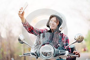 Young girl riding a motor scooter on road.