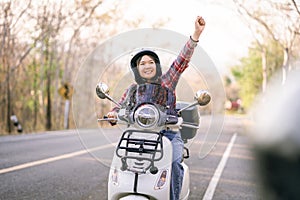 Young girl riding a motor scooter on road.