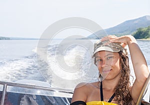 Young girl is riding on motorboat on the river in summer afternoon.