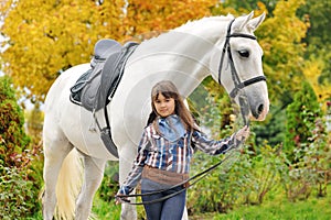 Young girl riding on white dressage horse