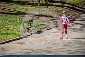 A young girl on roller blades passes a park bench