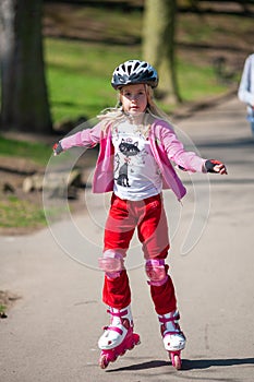 A young girl on roller blades wearing protective equipment