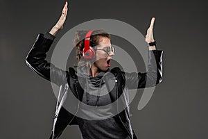 A young girl with rough facial features in a black jacket listens to music isolated on black background