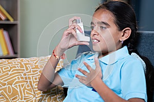 Young girl rubbing her chest after taking asthmatic inhaler at home - Concept of Teenager kids healthcare and medical