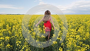 Young girl running through canola field - camera follow