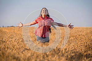 Young girl running on field with ripe wheat