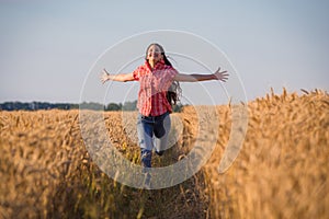 Young girl running on field with ripe wheat