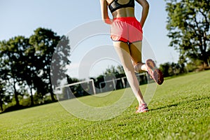 Young girl is running on green field, training concept