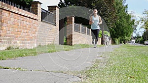 Young girl running with pet dog on leash