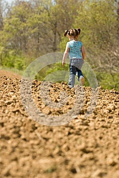 Young Girl Running on a Plowed Field