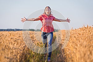 Young girl running on ripe wheat field