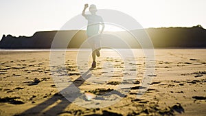 Young Girl Running On The Sand On A Peaceful Beach In The Setting Sun Light