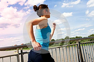 Young girl running in thr city, over the river by the bridge,