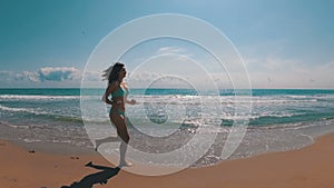 Young Girl Runs along the Beach of the Sea Coast in Slow Motion