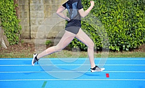 Young girl runs on the athletics track during sports training