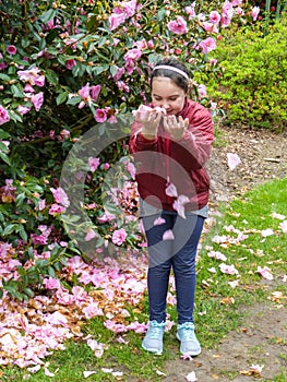 Young girl`s spontaneous, joyful play with rose-pink flower petals.