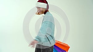 Young girl in Santa Claus cap holding color shopping bags