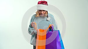 Young girl in Santa Claus cap holding color shopping bags