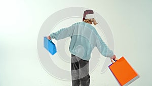 Young girl in Santa Claus cap holding color shopping bags