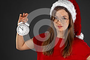 Young girl santa claus hat holding an white alarm clock
