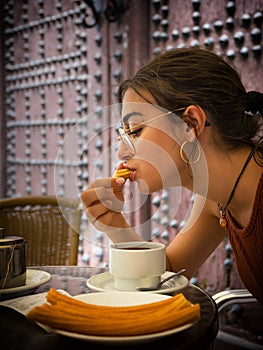 Young girl savors a snack of churros and a cup of hot chocolate photo
