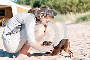 Young girl scratching her lovely dog`s back on summer beach