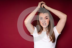 A young girl screams from a headache, clutching and tousling her hair and frowning. Strong pain photo