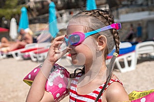 Young girl by the sea puts on her diving googles