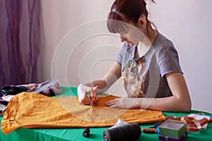 A young girl seamstress cuts out a mask pattern with scissors.