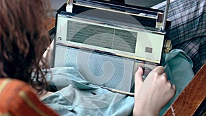 Young Girl searching for a radio station frequency on a vintage radio receiver