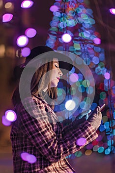 Young girl sending sms christmass wishes during winter alone in