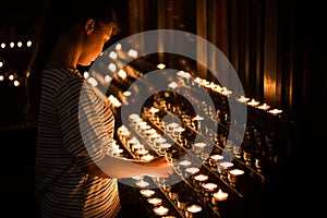 Young girl sets fire to a candle in the church before the prayer