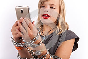 Young girl shackled with a chain using smartphone.