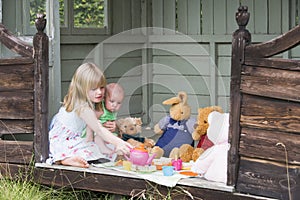 Young girl in shed with baby playing tea