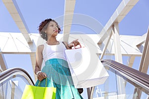 Young girl with shopping bags in her hands going down the mechanical stairs of a shopping center