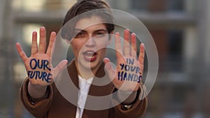 Young girl with a short haircut with an inscription on her hand - our future is in your hands. Global climate change