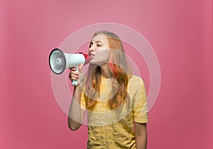 Young girl shouting in megaphone to announce news, information on pink studio background. Advertising, promotion concept