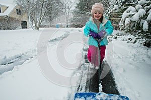 A young girl shoveling snow in a winter storm